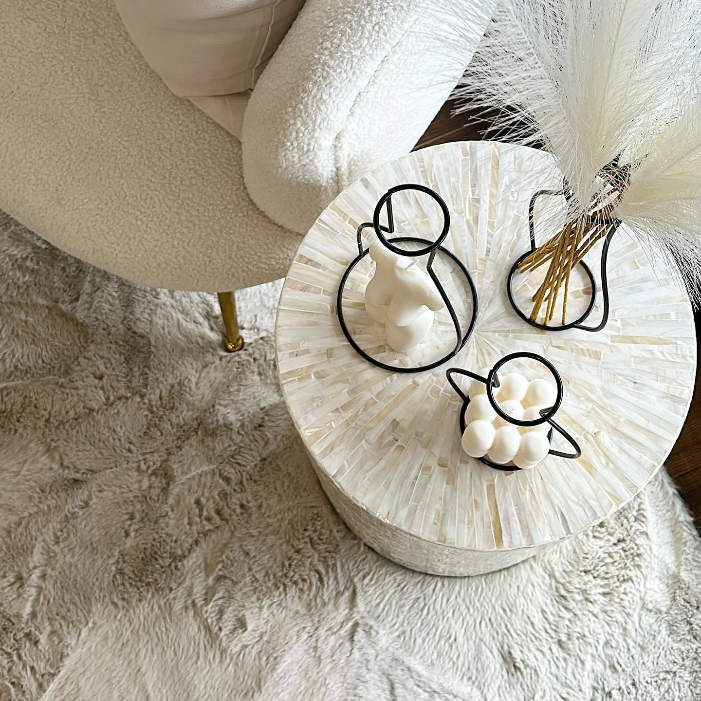 Side table with sculptural candles beside a boucle chair